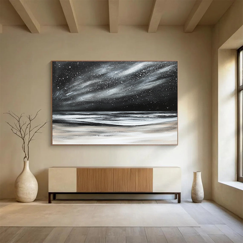 Large abstract painting depicting a dark stormy sky with stars and snow on the beach in black and white colors.SC295