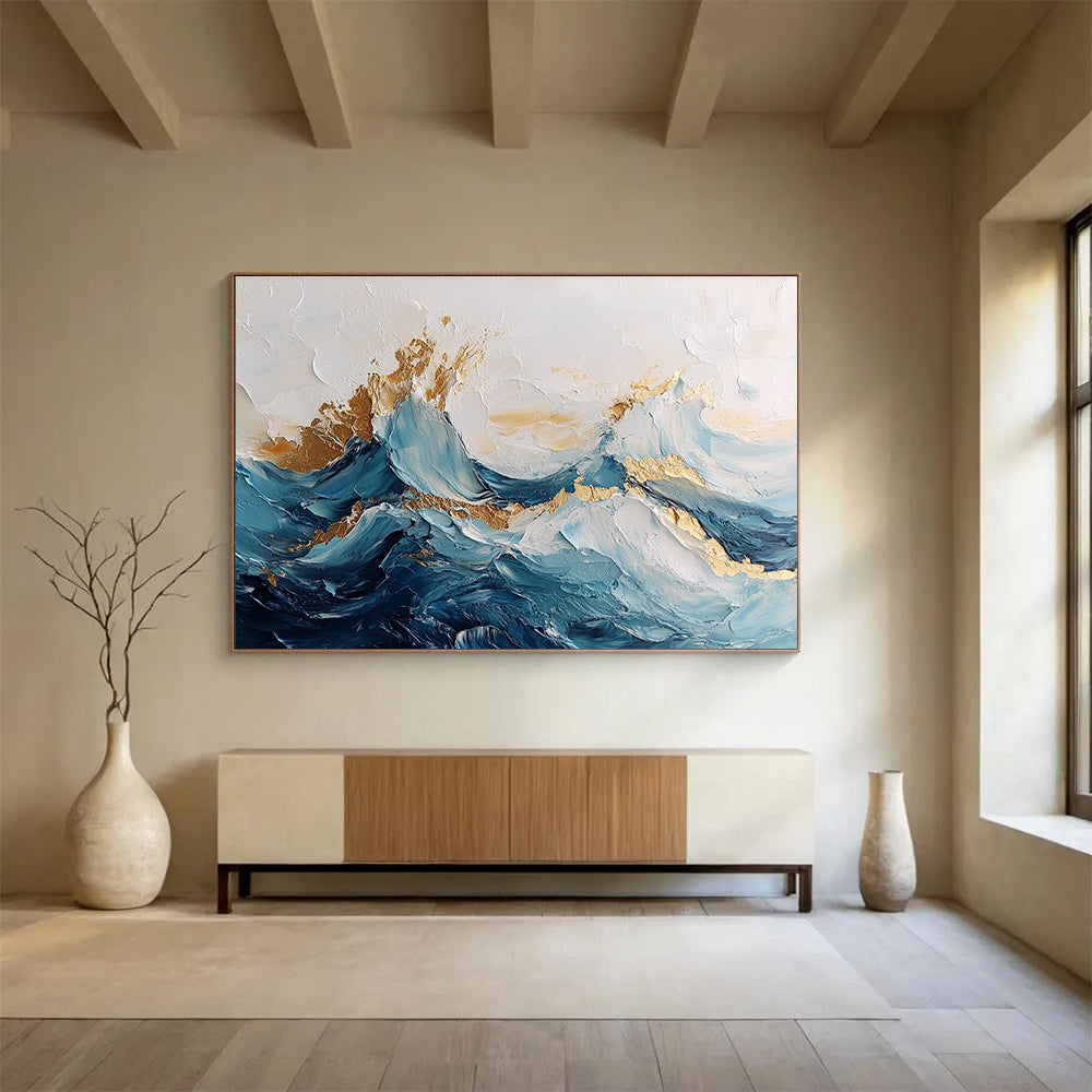 Large abstract painting of ocean waves in blue and white with gold accents featuring textured brush strokes and fluid shapes that convey movement.SC101
