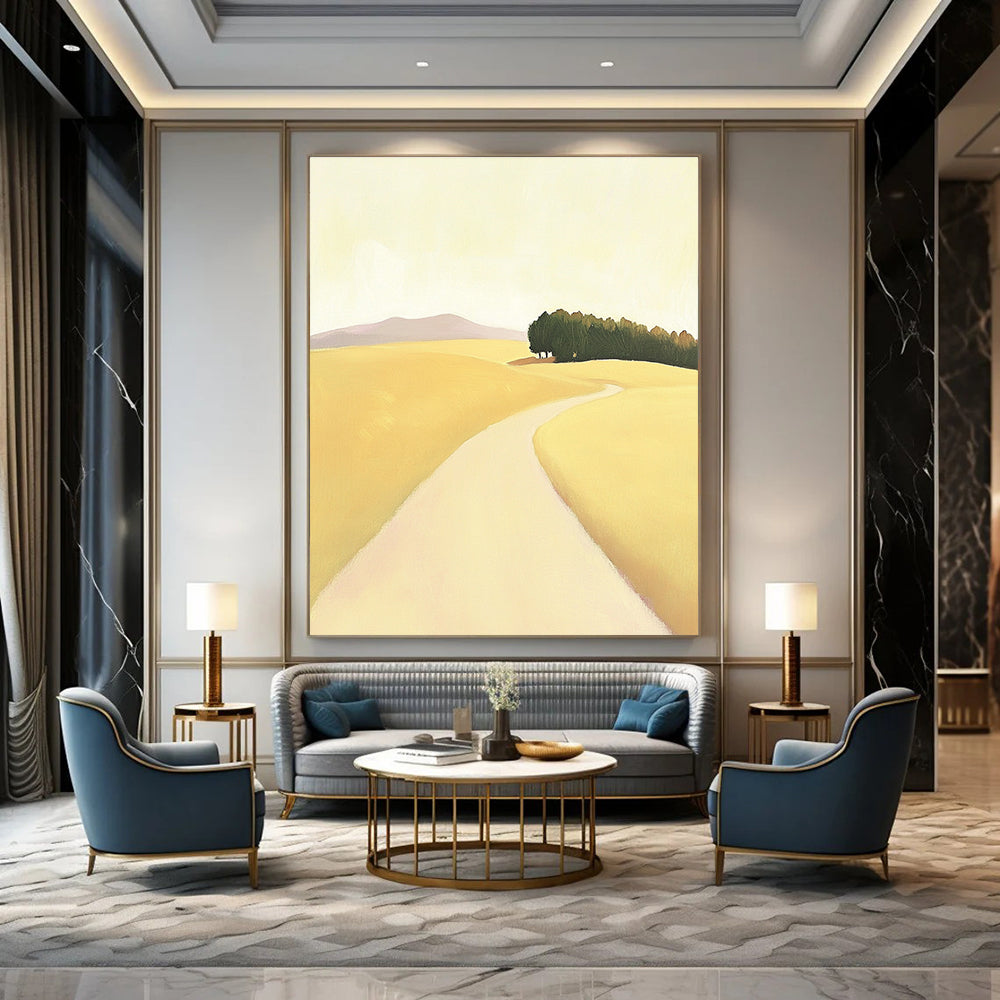 A large abstract painting depicting a minimalist road in an open field with hills and trees in soft yellow beige and green tones.STSC1167