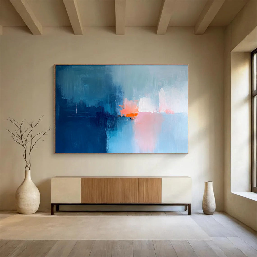 Large abstract painting in soft blue tones with pink and orange accents creates a serene mood through expressive brush strokes and blurred edges.SC253