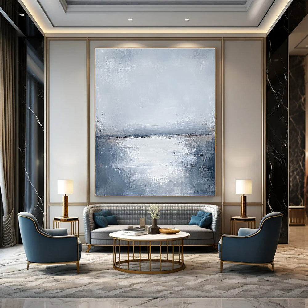 Large abstract painting featuring muted grays and soft blues capturing the serene connection between sunlit water and a cloudy sky.STSC464