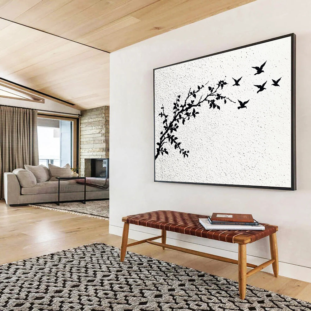 A large abstract painting featuring delicate branches with leaves and black and white flying birds against an off-white wall.SC434