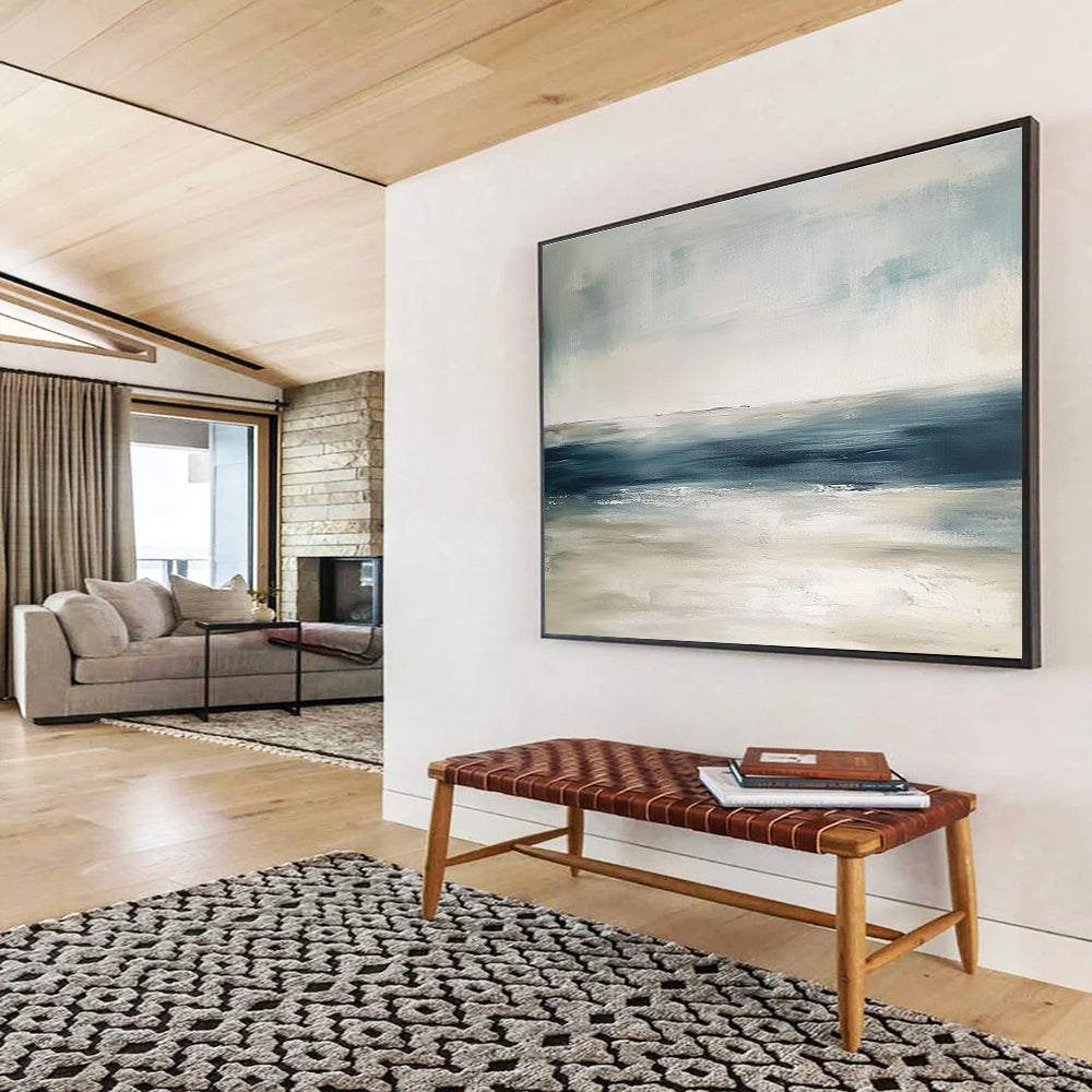 Large abstract painting featuring tranquil blue and gray tones with sandy beige hints soft brushstrokes evoke a serene ocean landscape.SC277