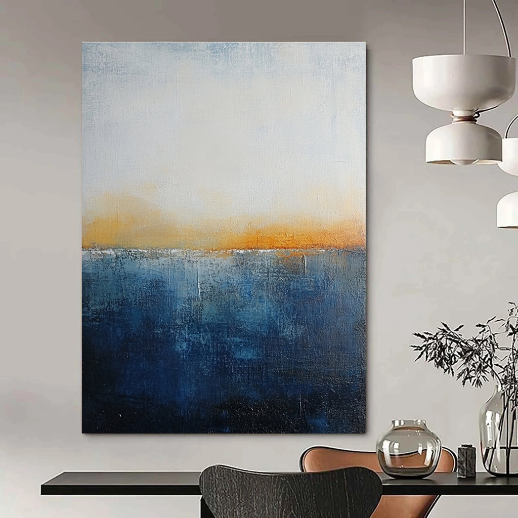 Large abstract painting with layered blue and yellow textures evokes oceanic depths at dusk with soft lighting enhancing movement and depth.STSC109