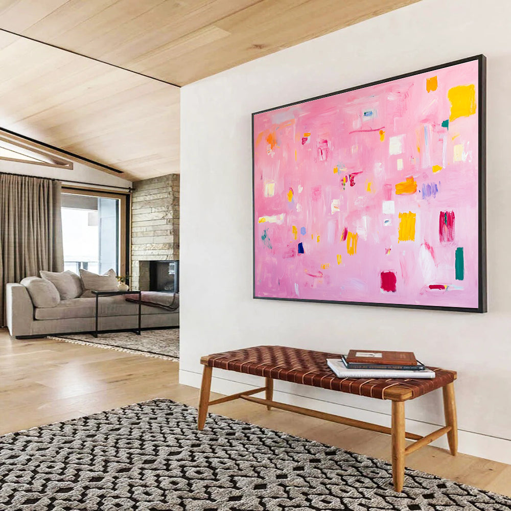A large abstract painting featuring soft pink hues bright yellow blocks red lines and white squares creates a joyful warm atmosphere perfect for celebration.SC536