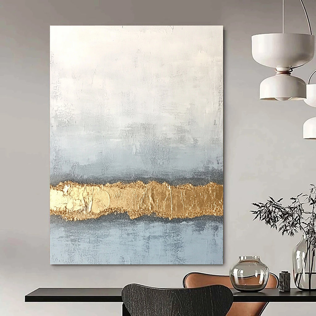 Large abstract painting with textured surface in soft gray and pale blue featuring a golden glitter line at the bottom.STSC735