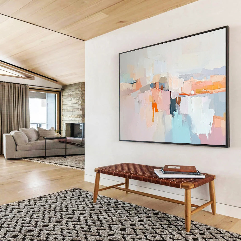 Large abstract painting in soft pastels featuring hills mountains a light grey sky peach-pink clouds and serene water for a calming effect.SC353