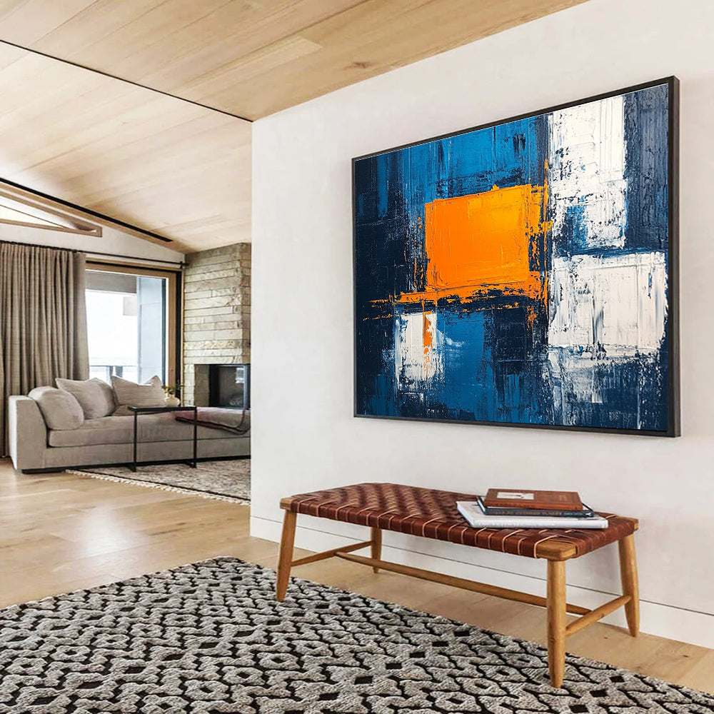 Large abstract painting featuring a textured pale blue background bold orange square white blocks and dark gray light indigo accents in acrylic.SC225