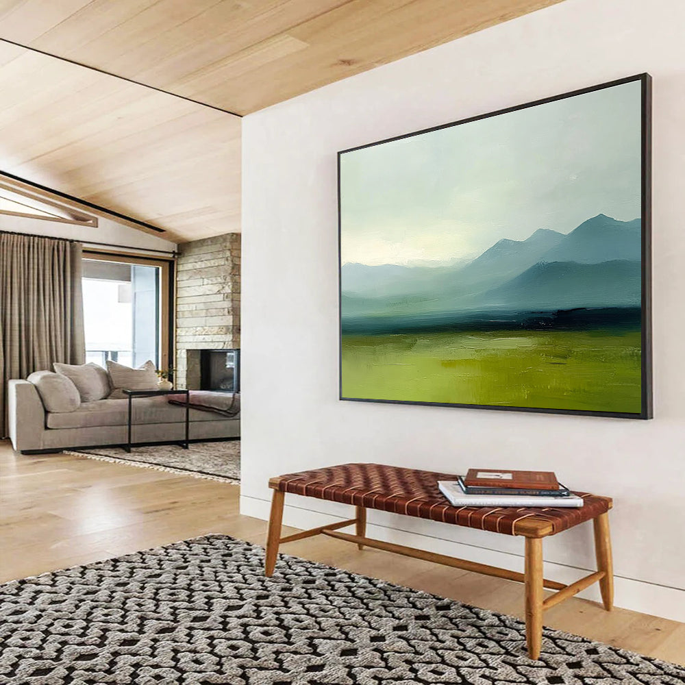 A large abstract oil painting depicting grassy plains and distant mountains in a minimalist style with a green and blue palette under a grey sky.SC409
