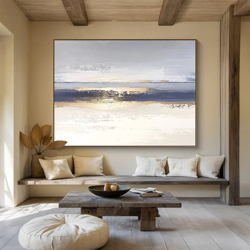 Large abstract painting with soft light blue and gray tones featuring metallic gold lines depicting water ripples on serene sand.SC007