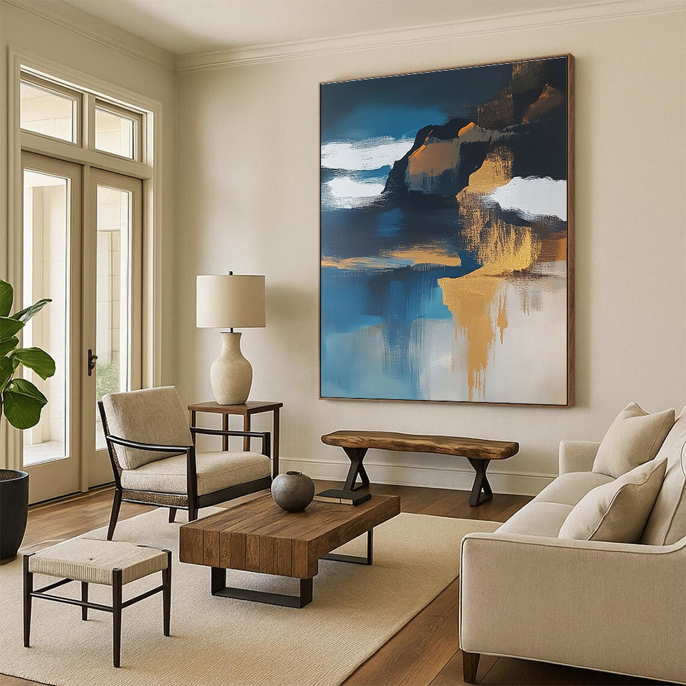 Large abstract painting of an island featuring navy blue water white clouds brown sand and gold leafing exuding a sense of calmness.STSC651
