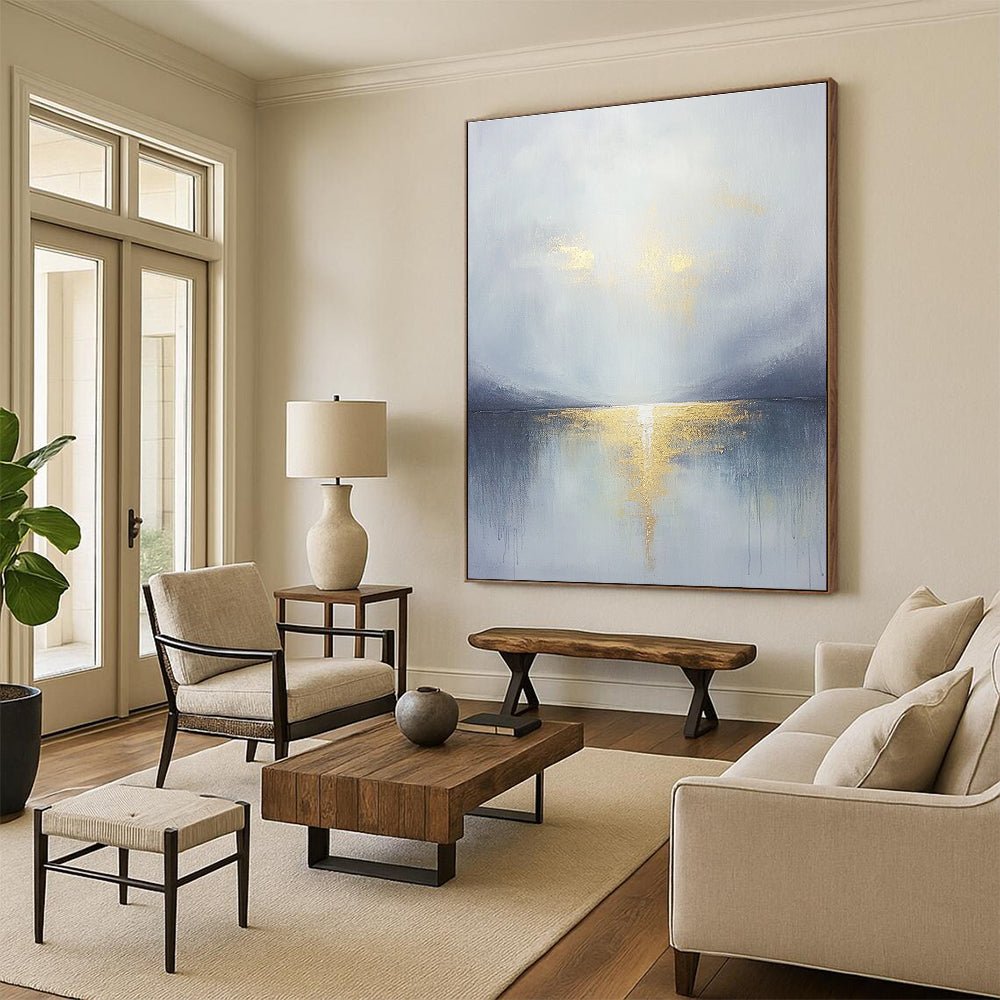 Large abstract painting featuring a grey sky clouds gold horizon and a tranquil lake in the foreground with soft muted colors.STSC289