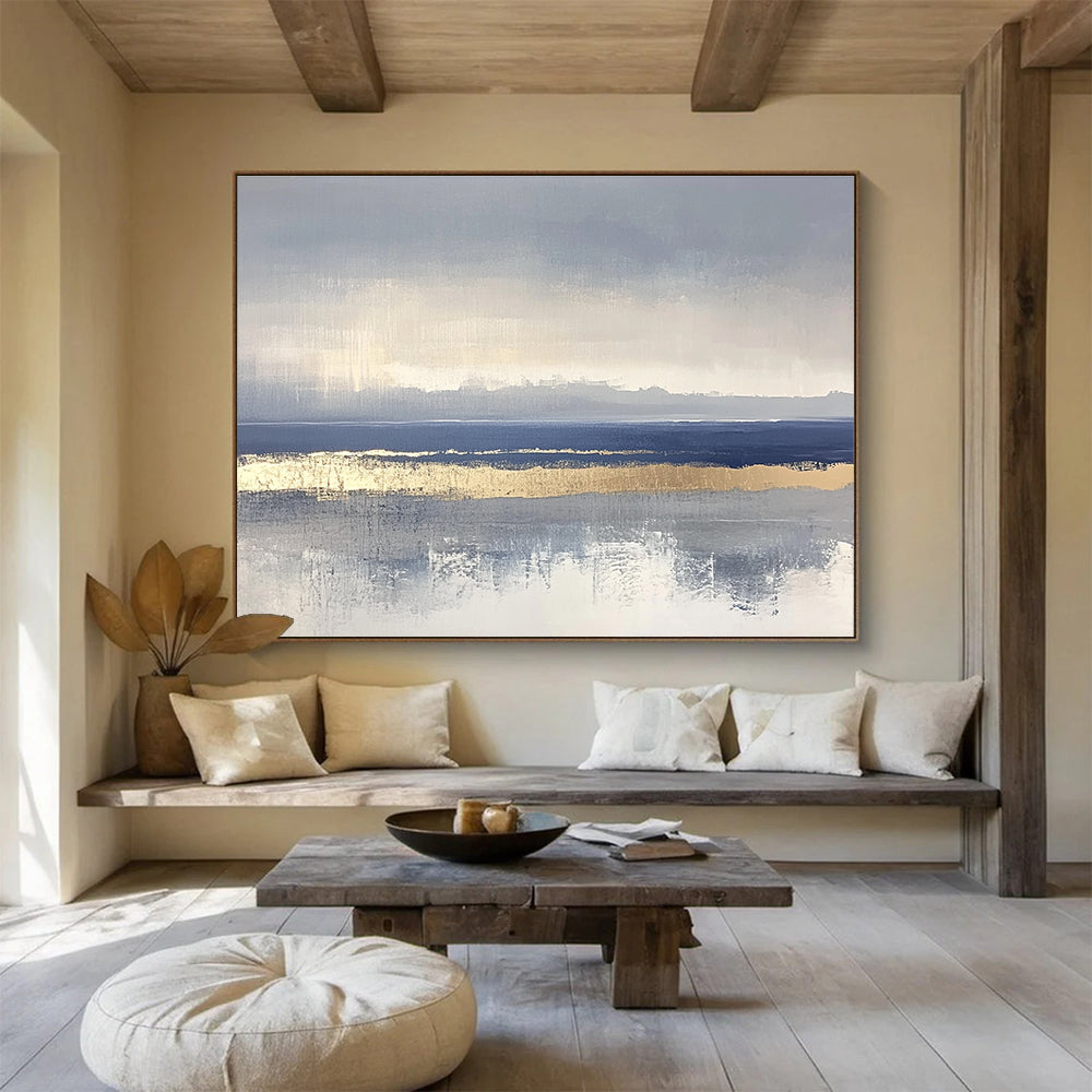 Large abstract painting featuring soft blue and gray tones with gold accents and visible brush strokes on a neutral background.SC038