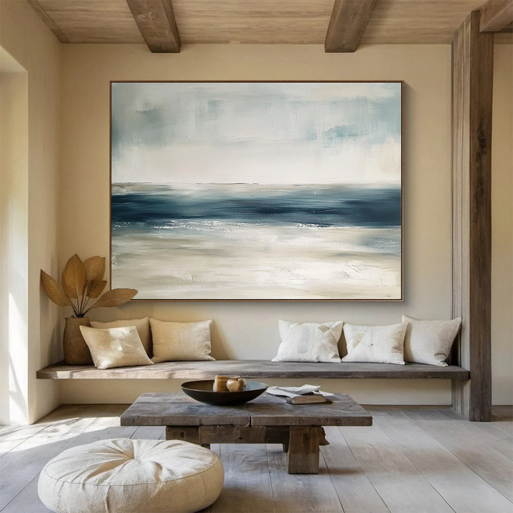 Large abstract painting featuring tranquil blue and gray tones with sandy beige hints soft brushstrokes evoke a serene ocean landscape.SC277