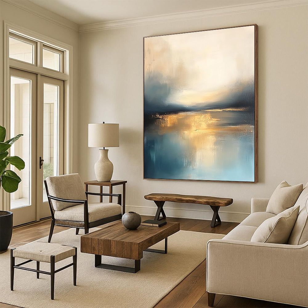 Large abstract painting featuring soft blue and gold tones with a calm sea reflections dramatic clouds and a tranquil sky.STSC103
