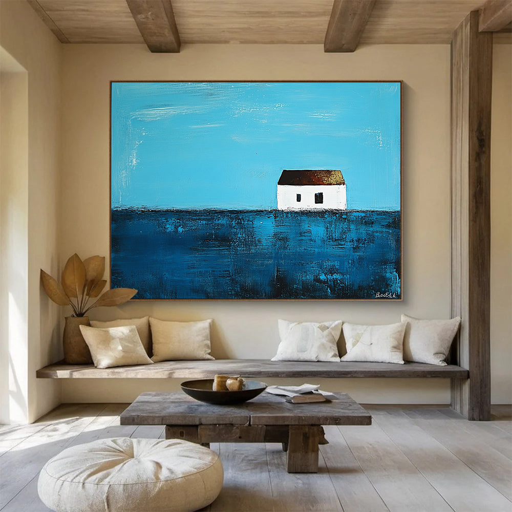 A large abstract painting featuring a small white house on the horizon surrounded by deep blue sea in the style of Anna Bocek.SC553