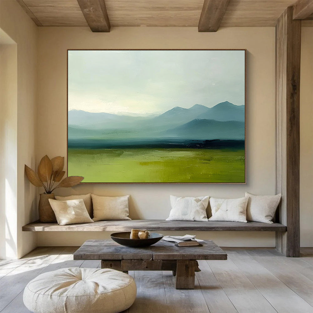 A large abstract oil painting depicting grassy plains and distant mountains in a minimalist style with a green and blue palette under a grey sky.SC409