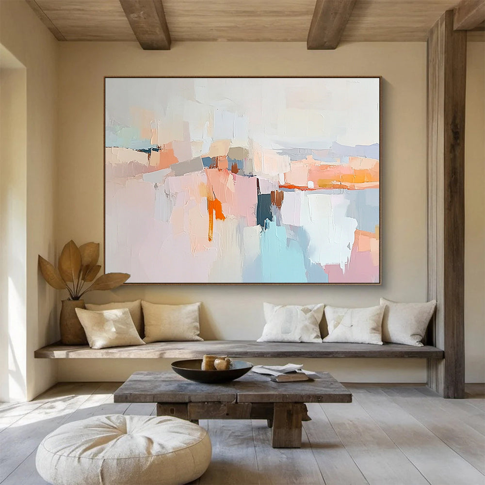 Large abstract painting in soft pastels featuring hills mountains a light grey sky peach-pink clouds and serene water for a calming effect.SC353