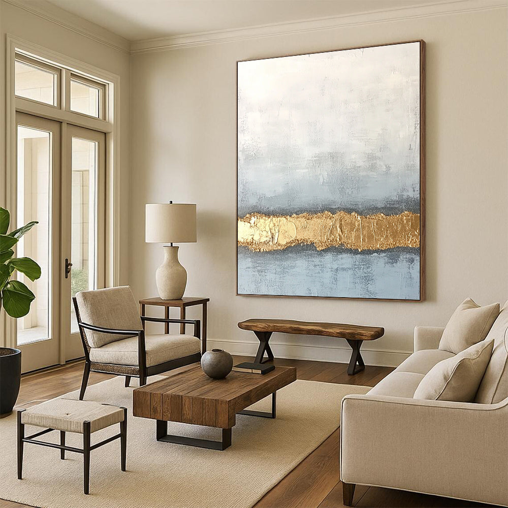 Large abstract painting with textured surface in soft gray and pale blue featuring a golden glitter line at the bottom.STSC735