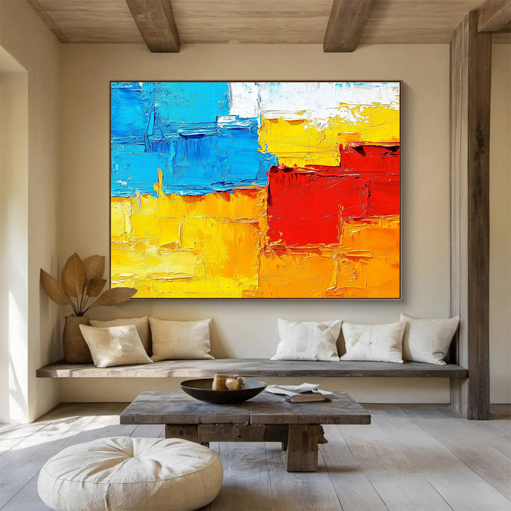 Large abstract painting featuring textured impasto brushstrokes in warm sunset tones of orange red yellow and blue.SC261