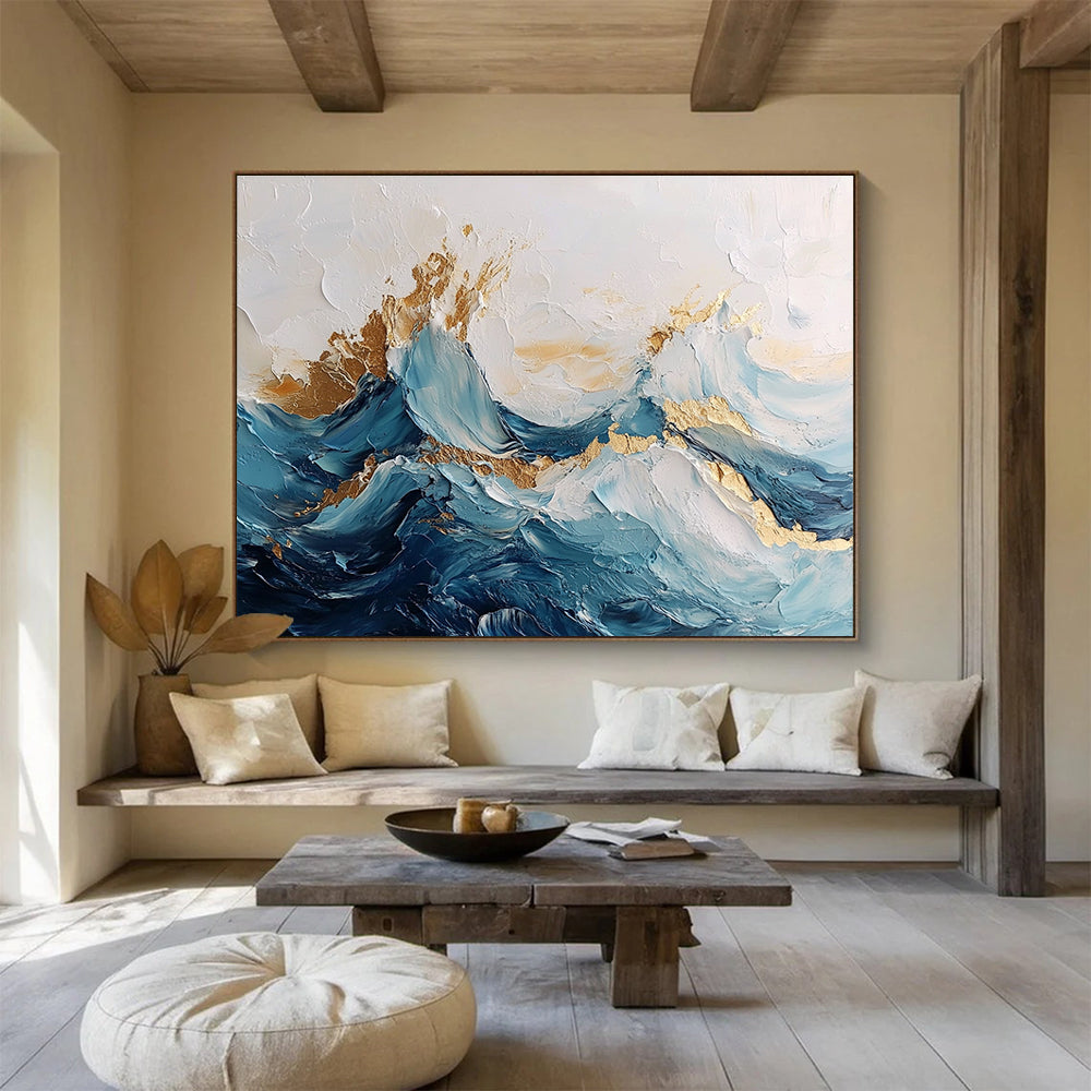 Large abstract painting of ocean waves in blue and white with gold accents featuring textured brush strokes and fluid shapes that convey movement.SC101