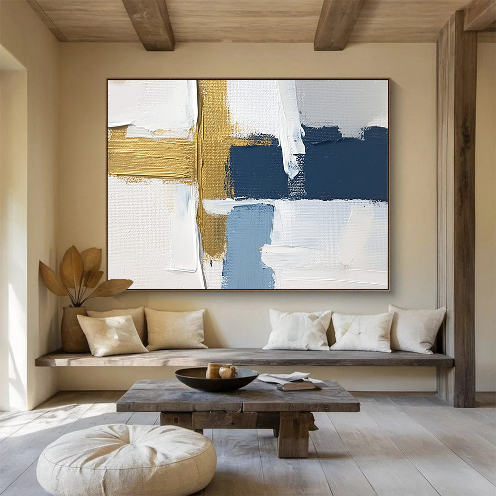 Large abstract painting with white blue and gold blocks featuring brushstrokes and texture showcasing a golden cross for depth in a serene atmosphere.SC267