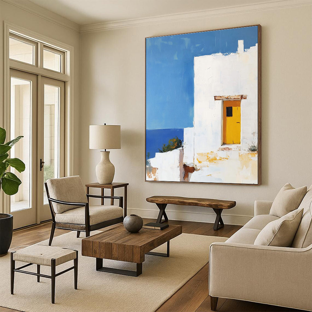 Large abstract painting featuring a white Greek house with a yellow door set against a blue sky in minimalistic style.STSC1252