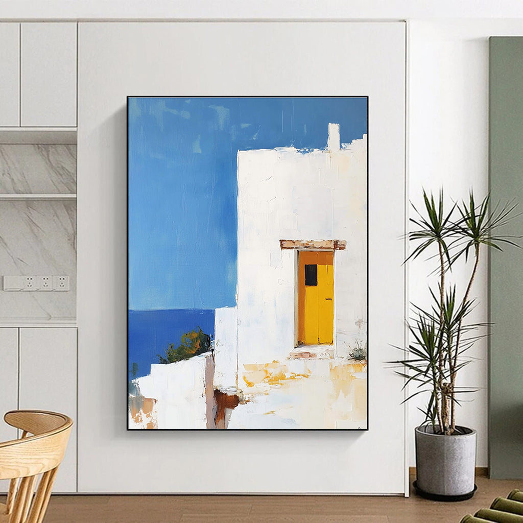 Large abstract painting featuring a white Greek house with a yellow door set against a blue sky in minimalistic style.STSC1252