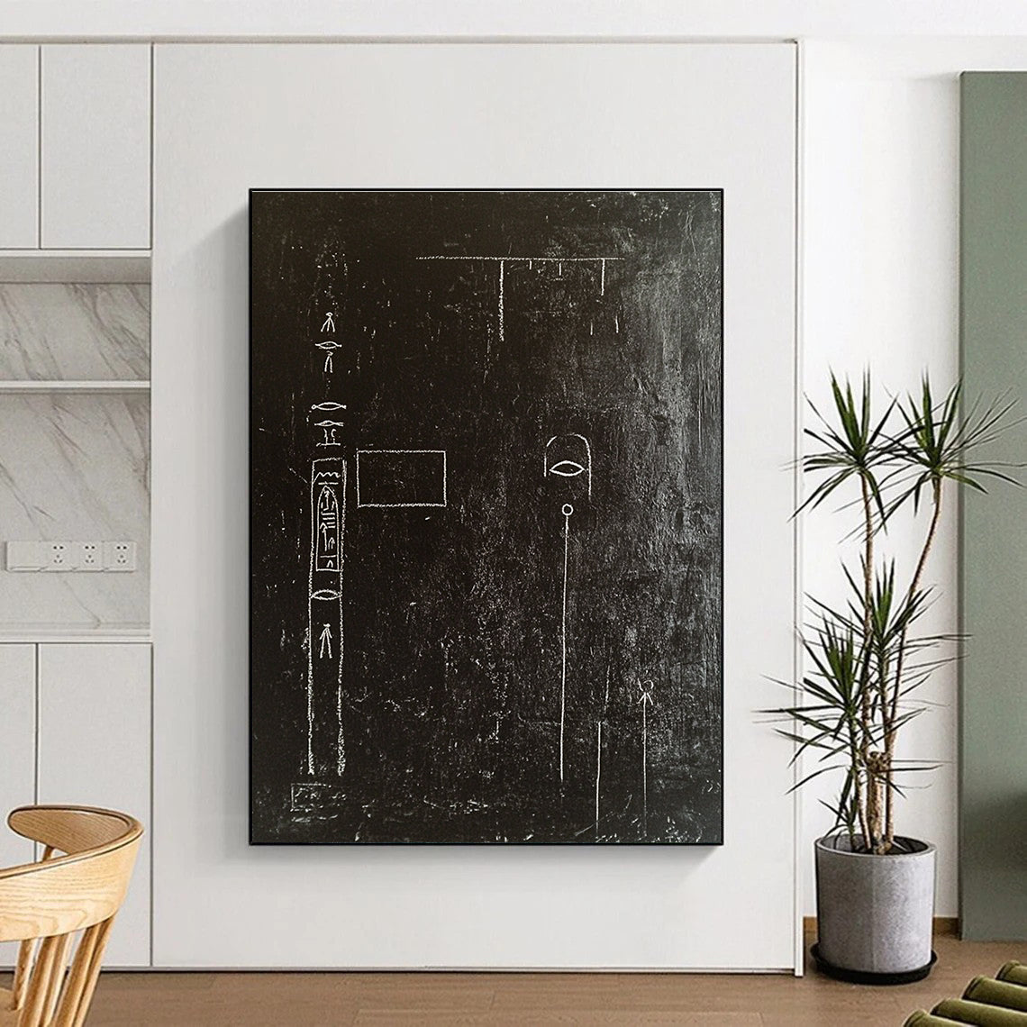 A large abstract painting featuring a black wall adorned with white chalk drawings of ancient Egyptian symbols and writing in high contrast.STSC918