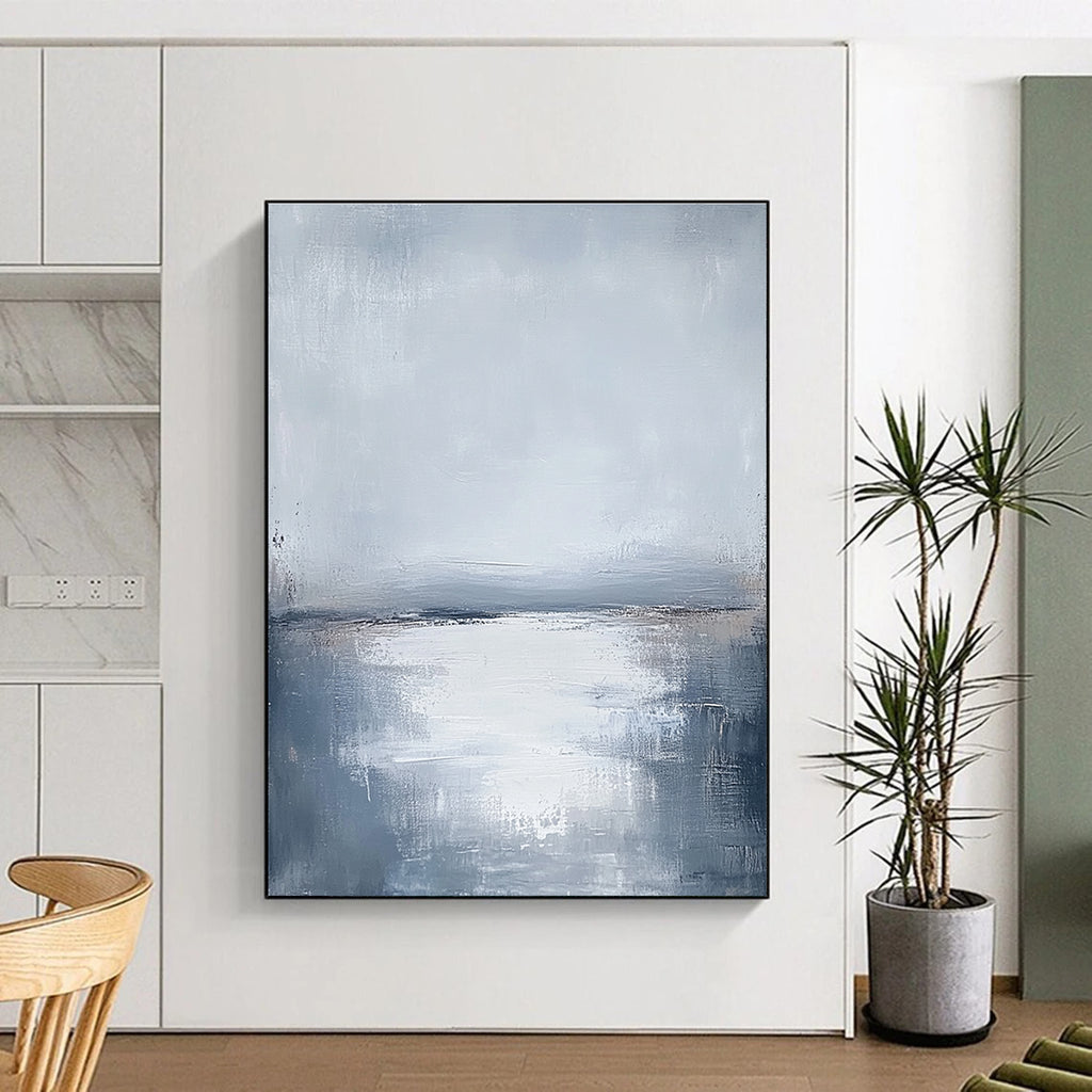 Large abstract painting featuring muted grays and soft blues capturing the serene connection between sunlit water and a cloudy sky.STSC464