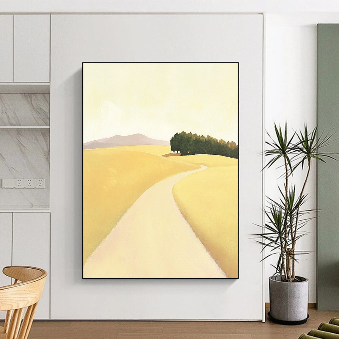 A large abstract painting depicting a minimalist road in an open field with hills and trees in soft yellow beige and green tones.STSC1167
