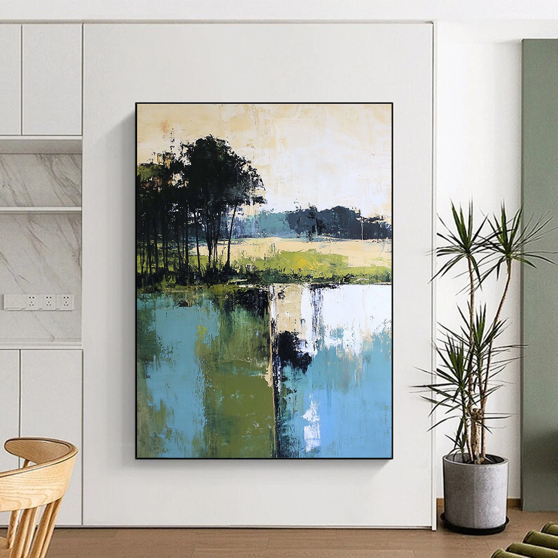 Large abstract painting featuring green blue and beige hues with distant trees foreground trees and green grass by the water.STSC098