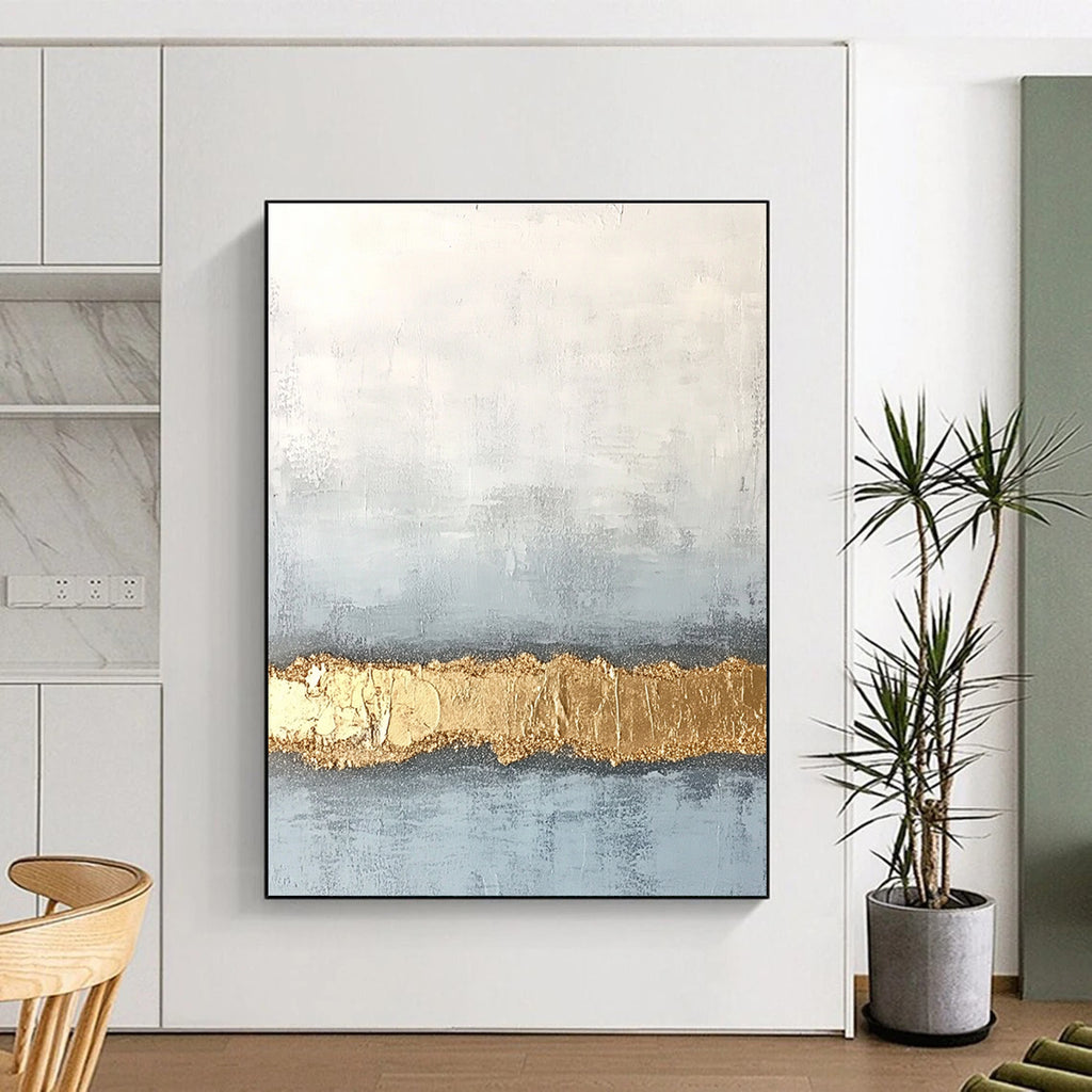 Large abstract painting with textured surface in soft gray and pale blue featuring a golden glitter line at the bottom.STSC735